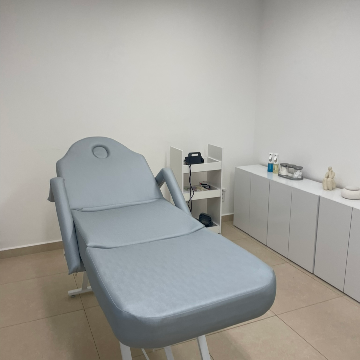Sala com uma maca em primeiro plano, dois móveis ao lado e ao fundo uma parede verde